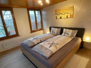 ein großes Bett in einem Zimmer mit zwei Fenstern in der Unterkunft Hälmli in Heiden