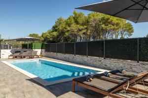 a swimming pool with an umbrella on a patio at Villa A in Bilice