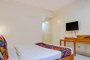 a small bedroom with a bed and a television at FabHotel Prime Ambassador in Pune