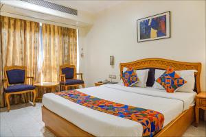 a bedroom with a large bed and two chairs at FabHotel Prime Ambassador in Pune