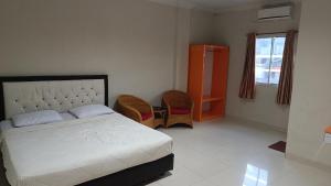 a bedroom with a bed and two chairs and a window at IHomestay Pekanbaru in Pekanbaru