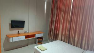 a room with a bed and a desk with a television at IHomestay Pekanbaru in Pekanbaru