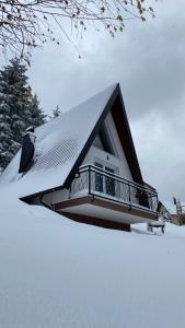 a house with a snow covered roof with a balcony at Alpi Cabin Pridolci in Busovača