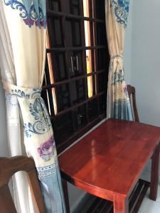 drewniany stół obok okna z zasłonami w obiekcie Hong Di Guesthouse w mieście Mui Ne