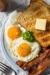 two eggs and bacon on a plate with toast at KUMA'S HOTEL in Weligama