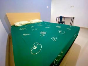 uma cama com um cobertor verde com desenhos em Alto Homestay em Palimbão