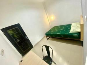 um pequeno quarto com uma cama verde e uma cadeira preta em Alto Homestay em Palimbão