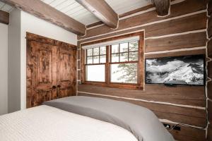 1 dormitorio con paredes de madera y 1 cama con ventana en Powder Ridge Cabin Manitou 19, en Big Sky