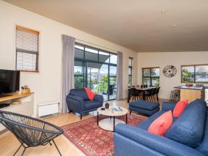 una sala de estar con sofás azules y una mesa. en Oceans 8 - Mangawhai Heads Holiday Home, en Mangawhai