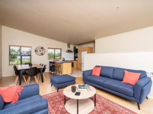 una sala de estar con 2 sofás azules y una mesa. en Oceans 8 - Mangawhai Heads Holiday Home, en Mangawhai