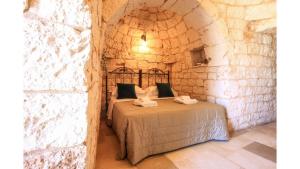 - une chambre avec un lit dans un mur en pierre dans l'établissement trullo degli ulivi con piscina e vasca per bambini, à San Michele Salentino