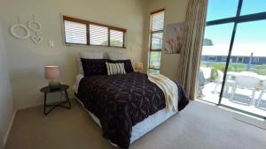 een slaapkamer met een bed en een groot raam bij Oceans 8 - Mangawhai Heads Holiday Home in Mangawhai