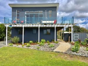 een blauw huis met een balkon erboven bij Oceans 8 - Mangawhai Heads Holiday Home in Mangawhai