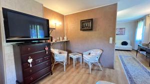 een woonkamer met een tv en een tafel en stoelen bij Chambres d'hôtes Le Muguet in Mandacou