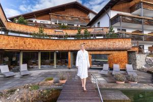 Kobieta w białej sukience schodzi po drewnianych schodach w obiekcie Biohotel Eggensberger w Füssen