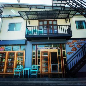 um hotel com cadeiras azuis em frente a um edifício em Tamtawan Guesthouse - ตามตะวันเกสเฮ้าส์ em Ko Lipe