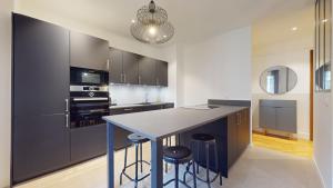 una cocina con encimera y una isla con taburetes en Beautiful modern apartment with balcony in Geneva, en Ginebra