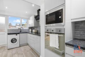 a kitchen with white cabinets and a washer and dryer at OnSiteStays - Spacious 3 Bed House with Garden, Wifi & 4 Plus Parking in Gravesend