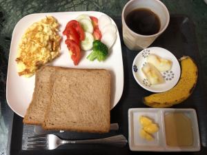 a plate of breakfast food with toast and fruit and a cup of coffee at Momotaro House in Bodh Gaya