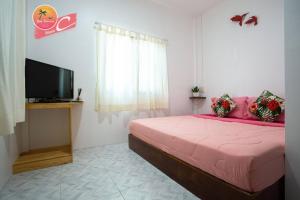 a bedroom with a pink bed and a flat screen tv at Tamtawan Guesthouse - ตามตะวันเกสเฮ้าส์ in Ko Lipe