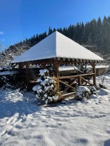 a wooden gazebo with a snow covered roof at Guest House Zator in Vyshkiv