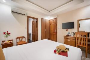 a bedroom with a large white bed with a hat on it at ELC Beach Hotel in Da Nang