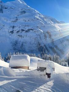 una casa ricoperta di neve di fronte a una montagna di Älpler Stuba Appartements am Lärchenhof a Warth am Arlberg
