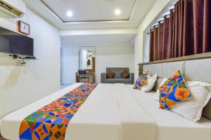 um quarto com uma grande cama branca com almofadas coloridas em FabExpress Radhe Residency em Ahmedabad