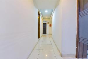 a hallway with white walls and a white tile floor at FabExpress Radhe Residency in Ahmedabad