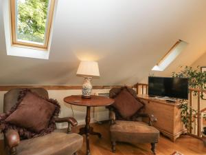 a living room with two chairs and a table and a television at The Barn at Westhall Cottage in Burford