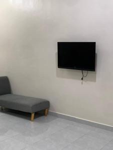 um quarto com uma cadeira e uma televisão de ecrã plano na parede em Zahra Homestay em Rantau Panjang