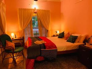 a bedroom with a bed and chairs and a window at Surendram Villa in Varkala