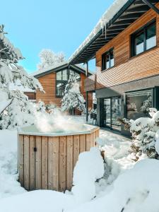 a hot tub in the snow in front of a house at ZSAM Chalets mit Sauna und Hottub in Garmisch-Partenkirchen