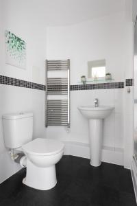 La salle de bains blanche est pourvue de toilettes et d'un lavabo. dans l'établissement Jade Apartments Basildon, à Basildon