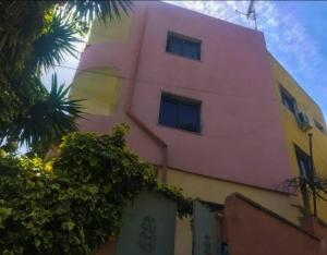 a pink building with a tree in front of it at Mance Apartment in Durrës