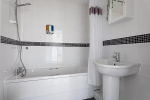 La salle de bains blanche est pourvue d'un lavabo et d'une baignoire. dans l'établissement Jade Apartments Basildon, à Basildon