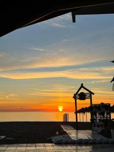 einen Sonnenuntergang am Strand mit der Sonne in der Ferne in der Unterkunft Apartamento Paseo de la Carihuela in Torremolinos