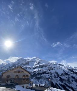 a building in front of a snow covered mountain at Älpler Stuba Appartements am Lärchenhof in Warth am Arlberg