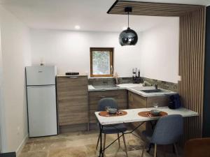 a kitchen with a white refrigerator and a table with chairs at Le studio Adhémar - parking sur place in Montboucher-sur-Jabron
