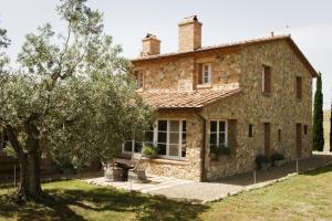 an old stone house with a tree in front of it at Villa La Salina in Bibbona