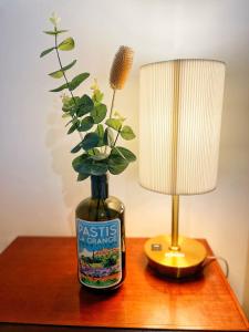 a table with a lamp and a bottle with a flower in it at Chambre Pastis in Eguisheim