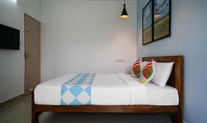 una camera da letto con letto, lenzuola e cuscini bianchi di FabHotel Majestic Heights a Ernakulam