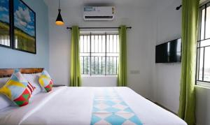 1 dormitorio con 1 cama grande y cortinas verdes en FabHotel Majestic Heights, en Ernakulam