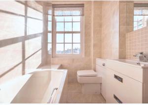 a bathroom with a tub and a toilet and a sink at Hyde Park Studio Flats in London