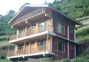 ein Haus mit Balkon an der Seite eines Hügels in der Unterkunft Mountain Bliss Cottages by StayApart in Shoja
