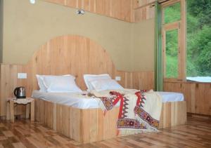 Schlafzimmer mit einem großen Bett mit einem Kopfteil aus Holz in der Unterkunft Mountain Bliss Cottages by StayApart in Shoja