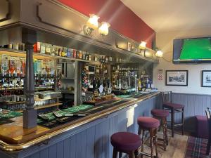 un bar con taburetes y TV en la pared en The Board Inn en Hawes