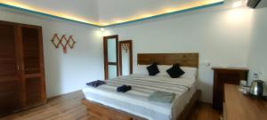 um quarto com uma grande cama branca com almofadas pretas em The Coast Beach Resort em Agonda