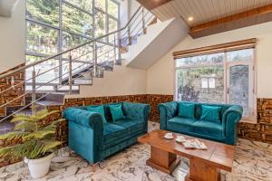un soggiorno con 2 divani blu e un tavolo di Treebo Trend Srishti Vaikunth With Mountain View a Shimla
