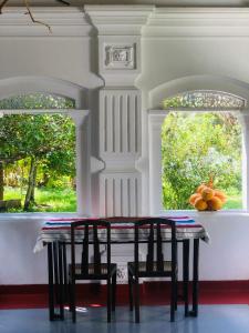 uma mesa e cadeiras num quarto com duas janelas em Anilau Vila em Hikkaduwa